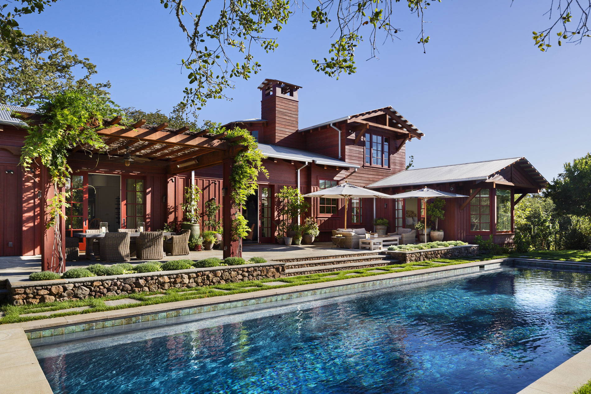 A bluestone terraces extends along the back façade of the house and overlooks a swimming pool. The western edge of the terrace features a Wisteria-covered dining pergola. (Photo credit: Peter Aaron/OTTO for Robert A.M. Stern Architects)