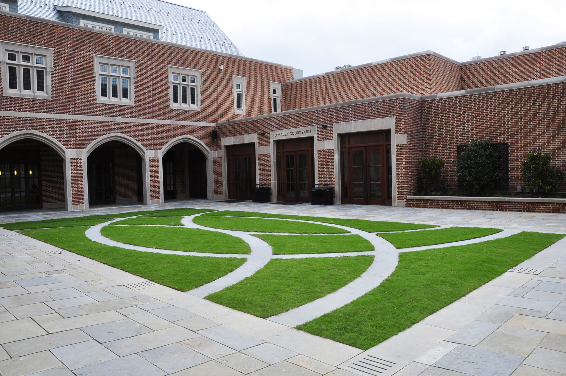 View of the courtyard showing lawn panel with bluestone bands, seat wall, and Camellias espaliered on trellises.